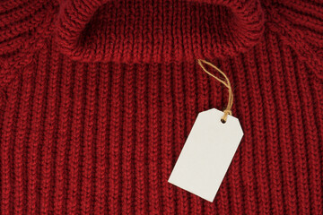 blank clothing tag, label mockup template on red knitted sweater.