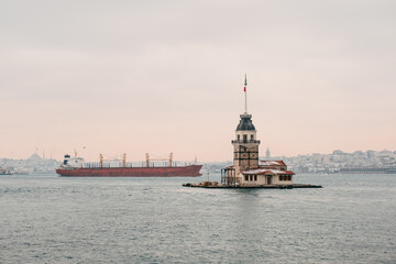 View of the Maiden Tower on the Bosphorus in Istanbul with a cargo ship sailing in the background.