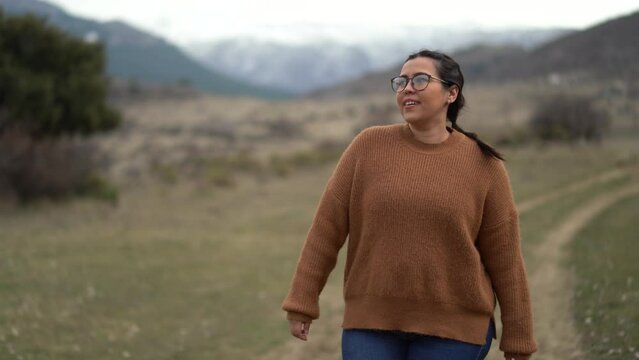 Chica caminando por camino de tierra con fondo de monta&ntilde;as nevadas