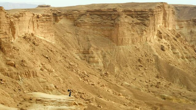 Aerial Panning A Woman In A Wind-Blown Dress Standing On The Edge Of A Desert Cliff - Riyadh, Saudi Arabia