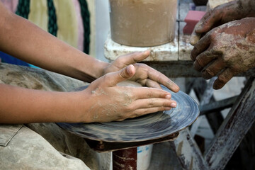 Naklejka premium The master teaches pottery. The hands of a potter and a child. Education concept.