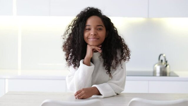 Portrait beautiful African American black girl at modern home Smiling young woman with curly hair looking at camera.