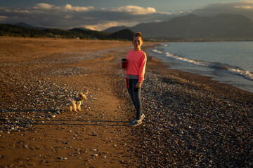 Woman walking on the beach with her dog. Training