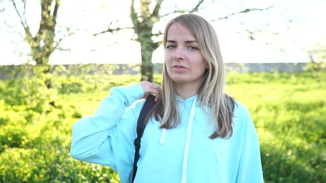 A beautiful girl in a blue hoodie. The girl straightens her hair. Blonde posing in front of the camera. Portrait of a girl of Slavic appearance.