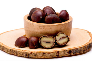 Obraz premium Group of roasted chestnuts on a wooden bowl isolated on a white background.