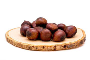 Group of roasted chestnuts on a wooden plate isolated on a white background.