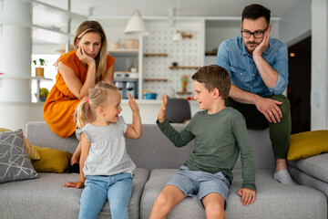 Tired parents sitting on couch feels annoyed exhausted while happy children playing together.