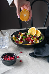 Female hands adding orange juice to fresh vegetable salad, vegetarian lifestyle