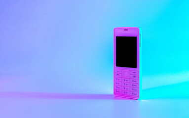 Retro cell phone vintage concept. White old mobile telephone in neon pink blue light. Retro wave. Pop art. minimal idea concept.