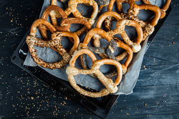 Fresh prepared homemade soft pretzels. Different types of baked bagels with seeds on a black background.