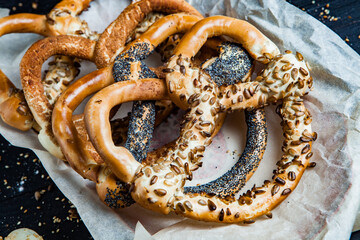 Fresh prepared homemade soft pretzels. Different types of baked bagels with seeds on a black...