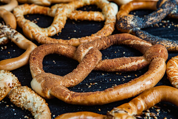 Fresh prepared homemade soft pretzels. Different types of baked bagels with seeds on a black background.