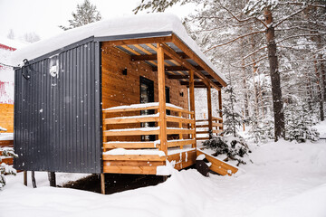 Modular house made of dark metal and light wood in winter forest. a house that takes into account...