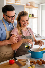 Attractive couple is cooking together organic healthy food in kitchen.