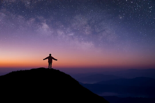 Silhouette of young traveler and backpacker open both arms and watched the star, milky way alone on top of the mountain. He enjoyed traveling and was successful when he reached the summit.
