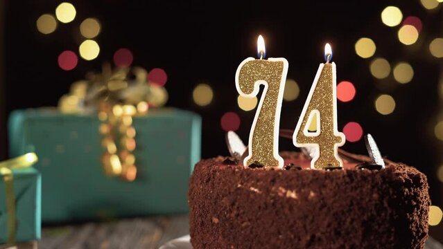 Number seventy-four birthday candle on a sweet cake on the table, 74th birthday. Fire from the lighter, blow out the holiday candle.