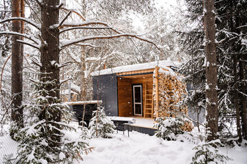 Modular house made of dark metal and light wood in winter forest. a house that takes into account everything you need for a comfortable life outside the city.