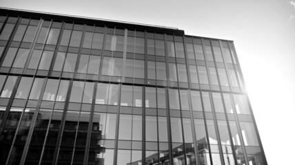 Fototapeta na wymiar Modern glass and aluminum wall of office building outdoor with bright sun rays falling. Black and white.