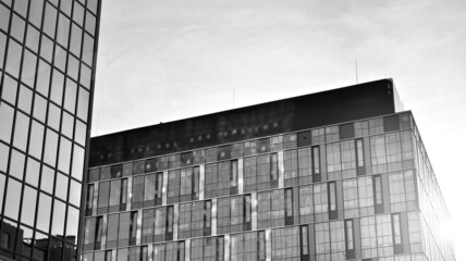 Modern glass and aluminum wall of office building outdoor with bright sun rays falling. Black and white.