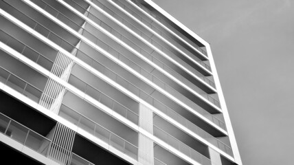 Obraz premium Modern luxury residential flat. Modern apartment building on a sunny day. White apartment building with a blue sky. Facade of a modern apartment building. Black and white.