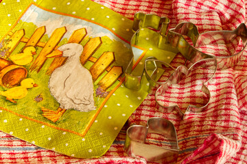 Preparing for Easter baking cookies and gingerbread cookies. Red checkered retro tea towel and green-yellow napkin with a spring theme. Goose with cubs. Metal cutters. Spring is coming. Home.