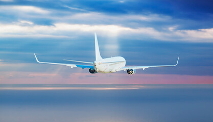 Obraz premium Airplane flying over tropical sea at sunset