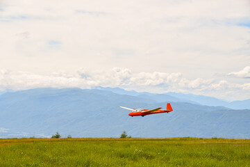 Fototapeta na wymiar A private monoplane flies in Japanese countryside with the epic grass meadow in summer Nagano.