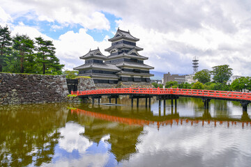 The red arch bridge connect across the deep moat to the Castle Matsumoto in summer Nagano, Japan.