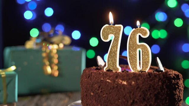 Number seventy-six birthday candle on a sweet cake on the table, 76th birthday. Fire from the lighter, blow out the holiday candle.