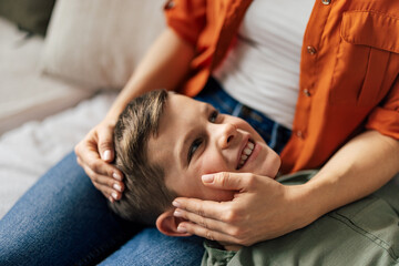 Closeup of young caucasian boy, laying on his mother's lap, while she holds him.