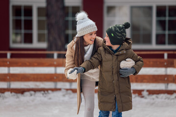 Mother's day, delighted brunette woman, holding her son from behind, on ice.