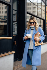 Fototapeta premium Women having a busy morning, holding cups of coffee and a loaf of bread, walking.