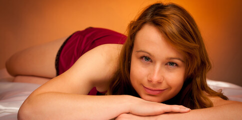 woman in lingerie lying on satin sheets in bedroom