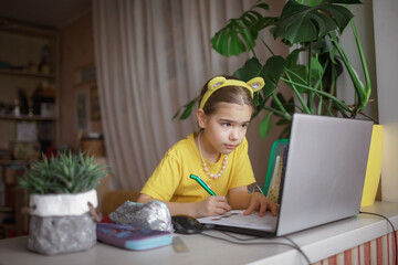 Distant education. Attentive schoolchild studying homework during online lesson at home, social distance during quarantine, self-isolation, communication via internet