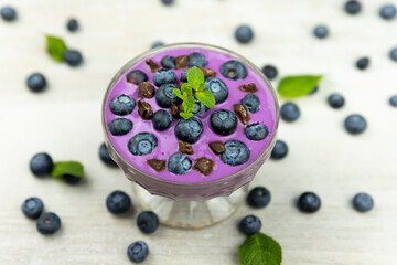Smoothie or pudding with blueberries and chocolate served in a bowl for breakfast. Top view image