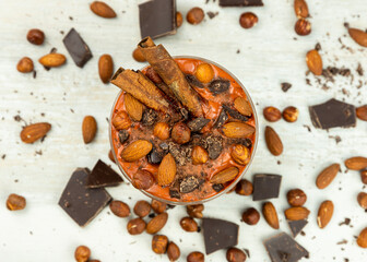 Smoothie or pudding with chocolate, hazelnuts and almonds served in a bowl for breakfast. Flat lay image