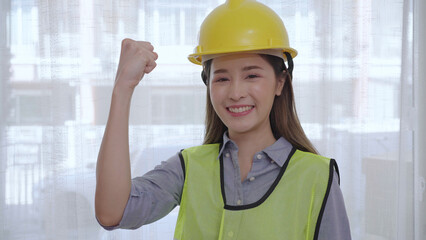 A beautiful Asian construction worker raises her right arm to show her diligence or fighting.