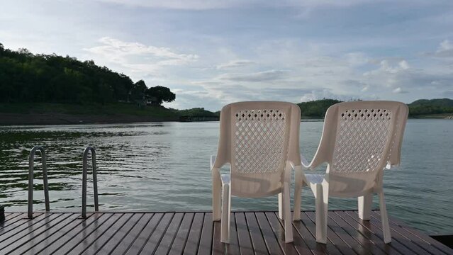 Two chairs sitting on balcony and facing on lake