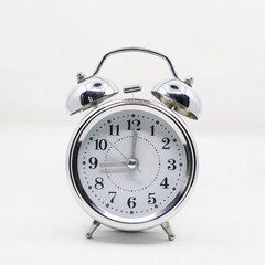 a vintage classic ringing alarm clock with a silver body and white analog dial isolated in a white background