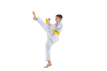 One sportive little boys, taekwondo athletes wearing doboks practicing alone isolated on white...