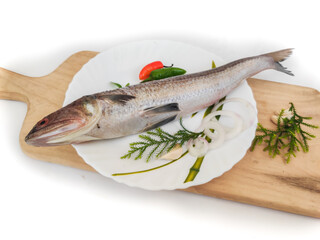 Greater lizardfish or wanieso saurida or Saurida tumbil decorated with herbs and vegetables on a wooden pad.Selective focus