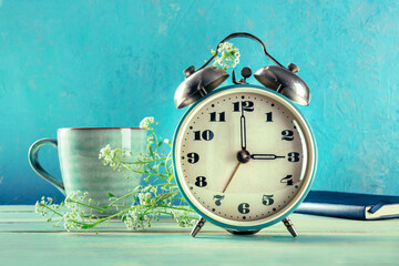 Daylight Saving Time concept, spring forward. A vintage alarm clock with coffee and fresh flowers...