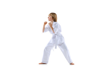 Portrait of sportive kid, male taekwondo, karate athletes in doboks jumping isolated on white background. Concept of sport, martial arts