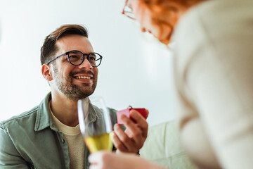 Smiling man holding red box with marriage engagement ring and make proposal to happy girlfriend.