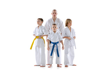 Portrait of group of kids, boys, taekwondo or karate athletes standing with master, coach isolated...