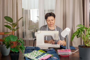 The woman behind the sewing machine sews a bag of old denim. Zero waste, hobby concept