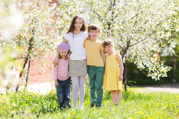 Fototapeta premium kids friends spend time together in nature. group of children of friends plays in a flowering garden 