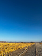 Fototapeta na wymiar Gravel road in desert. Sandy landscape, nobody. Nature in Namibia, Africa