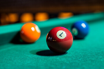 beautiful multi-colored balls with numbers lie under the light of lamps on the pool table.