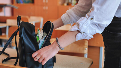 The schoolgirl puts the books in the bag after school.